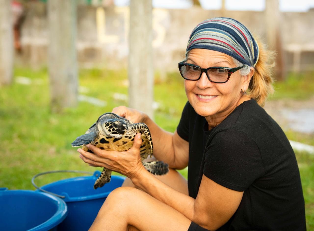 Ofelia Méndez sosteniendo una tortuga carey durante una jornada de conservación de tortugas marinas de Ocean Soldiers